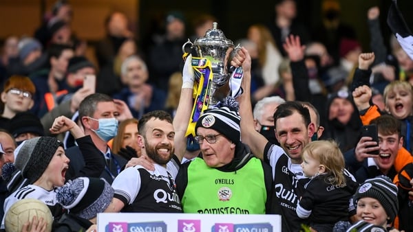 Kilcoo joint-captains Conor Laverty, left, and Aidan Branagan lift the Andy Merrigan Cup with manager Mickey Moran