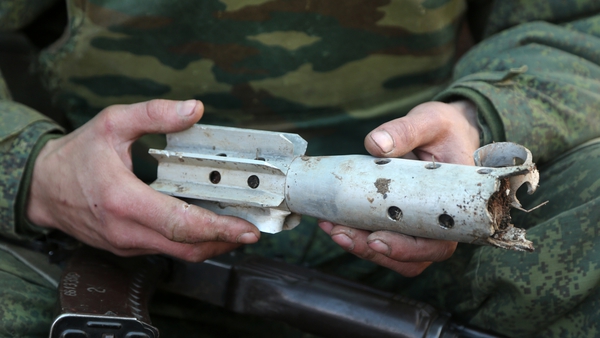 A serviceman of the Donetsk People's Militia holds a fragment of a shell fired at the front line near the rural town of Staromikhailovka