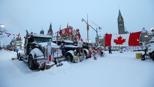 Demonstrators appeared to dig in after a heavy snowfall, playing cheerful music and waving Canadian flags at the ends of hockey sticks