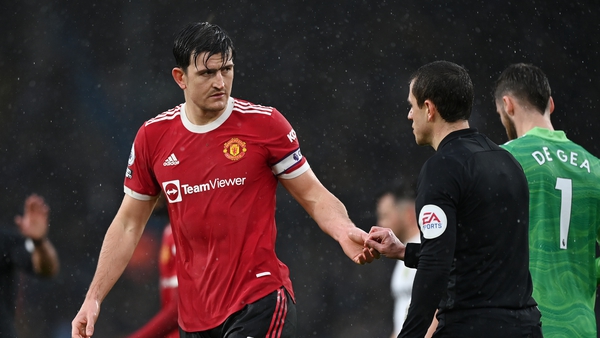 Manchester United captain Harry Maguire hands an official a coin thrown onto the pitch