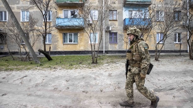 A soldier walks by a building damaged by bullets and cannon balls at Schastia town, Luhansk