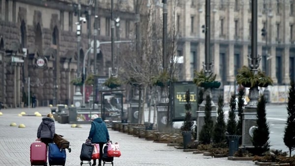 Women carry their belongings on a deserted street in Kyiv