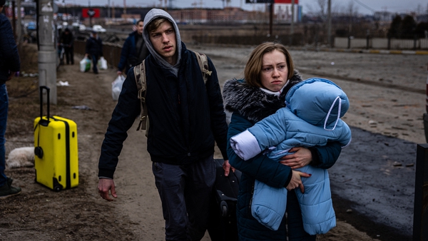 A woman carries her child as they flee the city of Irpin, northwest of Kyiv