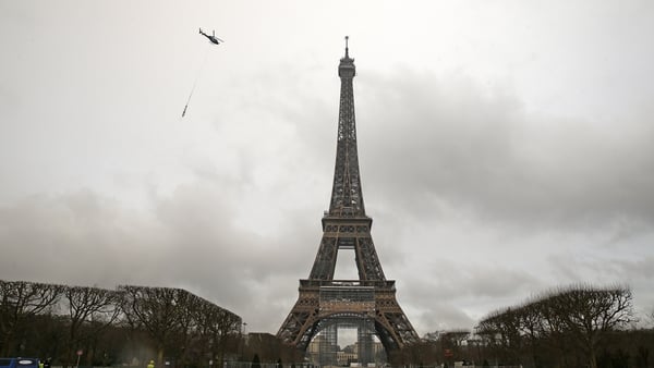 A helicopter moves into position to fix the new antenna on the Eiffel Tower
