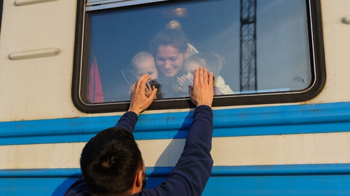 A man gestures to his family outside a train to Poland at Lviv Railway station