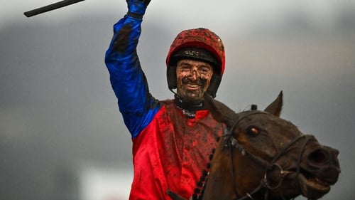 A mud-splattered Patrick Mullins celebrates after riding Facile Vega to victory in the Weatherbys Champion Bumper
