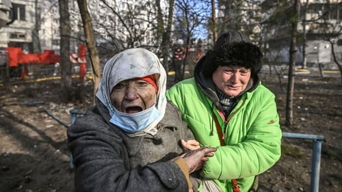 A woman is evacuated from a burning apartment building in Kyiv on Tuesday