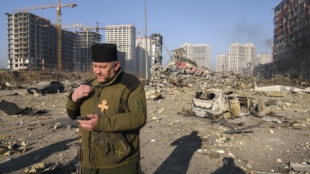 A military chaplain prays in the rubble of a destroyed shopping centre in Kyiv's Polil district