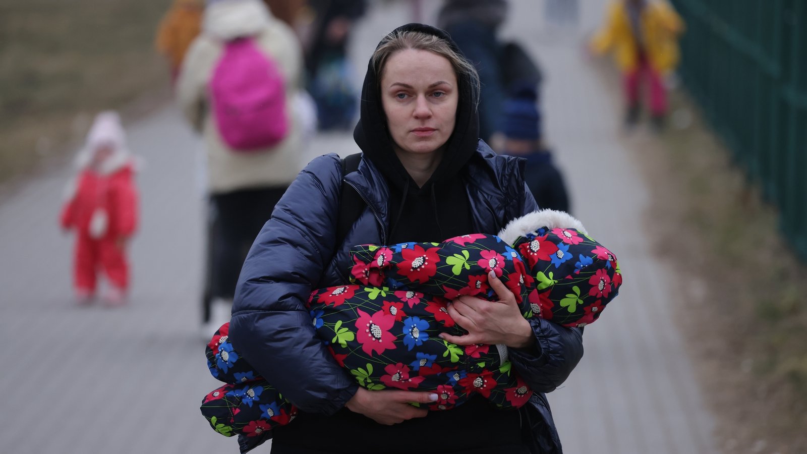 Image - A mother carrying an infant arrives in Poland at the Medyka border
