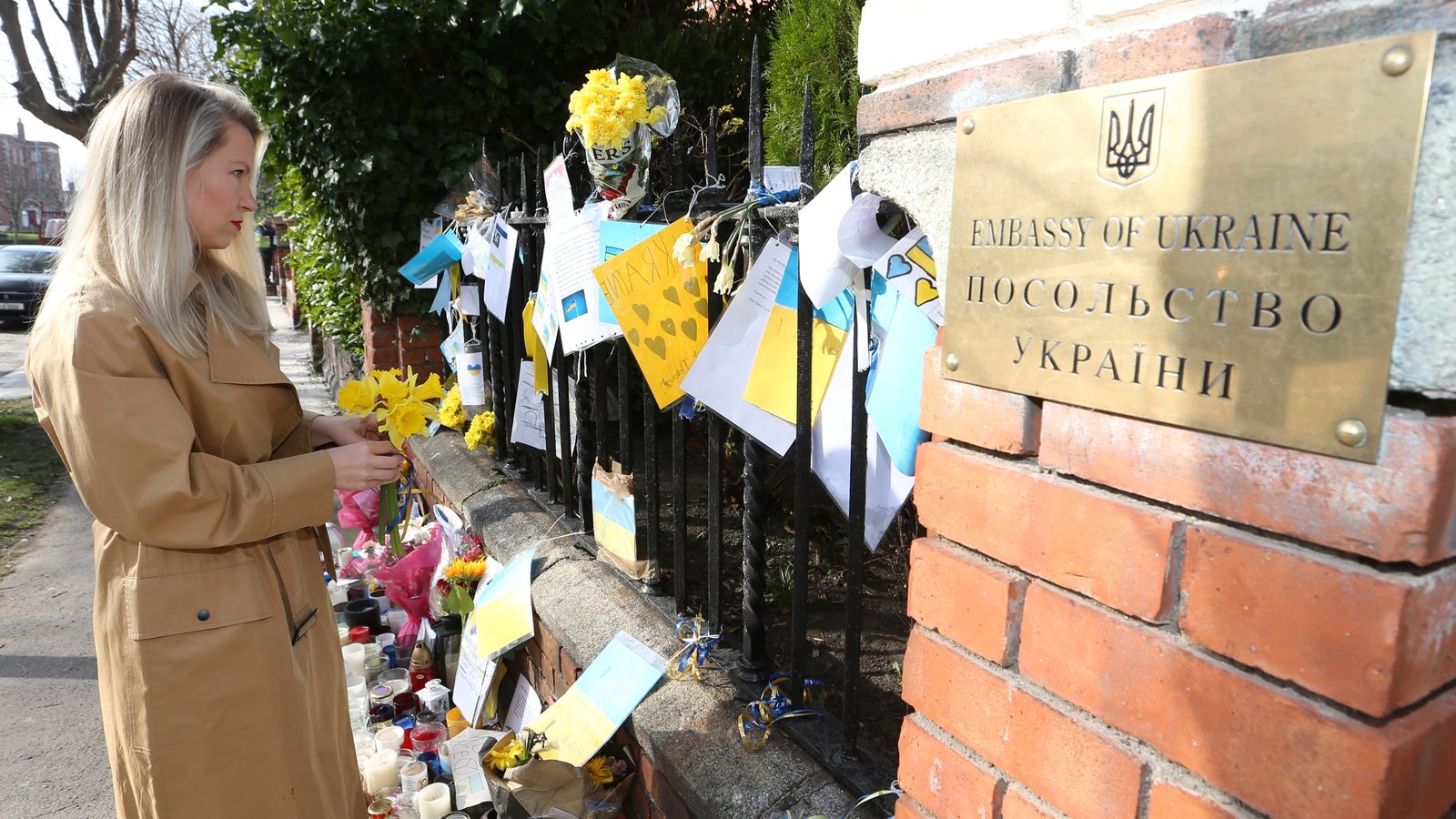 Image - A woman looks at flowers and messages of support for the people of Ukraine outside the Ukraine embassy in Dublin (Pic: RollingNews.ie)