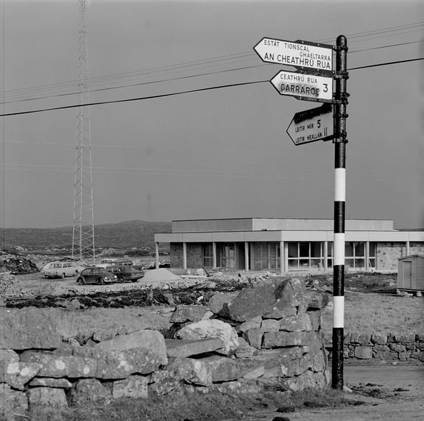 An exterior view of RTÉ Raidió na Gaeltachta's premises in Casla, Connemara, County Galway, with a signpost in the foreground, in February 1972.  2210_051_rnag