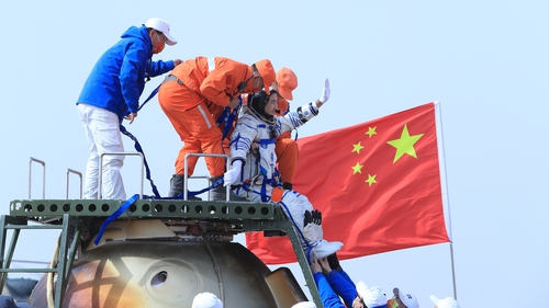 Astronaut Zhai Zhigang waves as he is helped to disembark after landing at Inner Mongolia