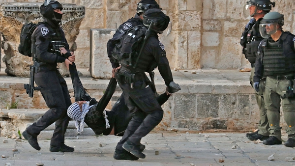 Israeli police carry a wounded Palestinian demonstrator during clashes at the Al-Aqsa mosque
