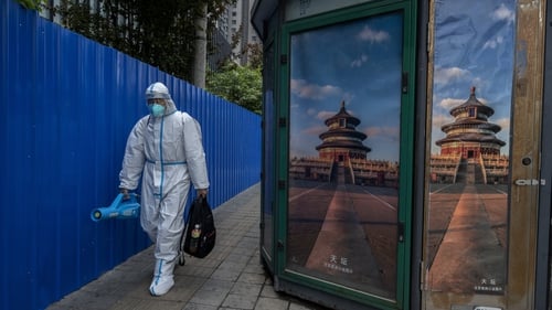 A health worker wears protective clothing as he walks past a kiosk in Beijing