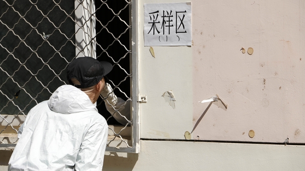 A medical worker tests a resident for Covid through a fence in Beijing this morning