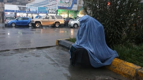 An Afghan woman sits beside heavy traffic in Herat, Afghanistan