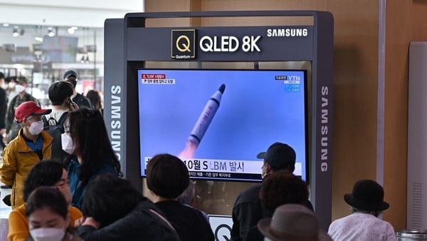 People watch a television screen showing a news broadcast with file footage of a North Korean missile test, at a railway station in Seoul