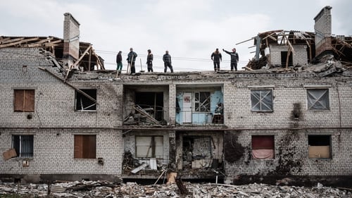 Workers clean rubble from a building destroyed by shelling in Cherkaske, eastern Ukraine
