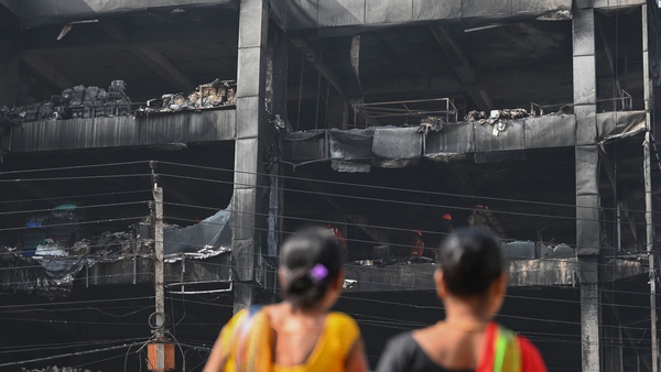 Onlookers gather outside a burnt down commercial building a day after a fire broke out in New Delhi