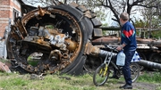 A local resident looks at a destroyed Russian tank next in the village of Mala Rogan, east of Kharkiv