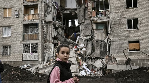 A young girl passes by a destroyed apartment building in Bakhmut in the eastern Ukranian region of Donbass