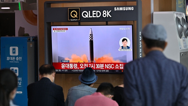 People watch a television screen showing a news broadcast with file footage of a North Korean missile test, at a railway station in Seoul on 25 May