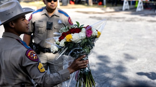 A Texas State Trooper receives flowers for the victims of a mass shooting yesterday at Robb Elementary School