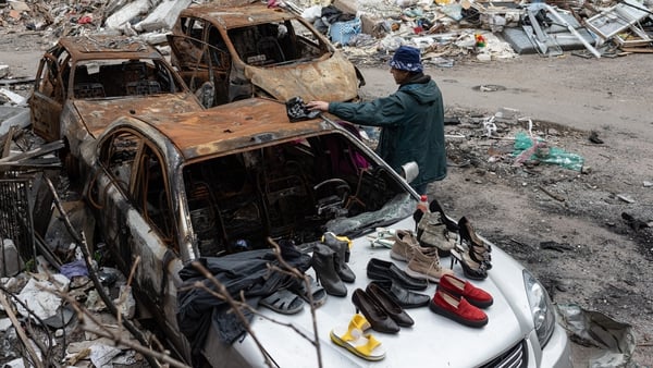 A man inspects shoes that people left on the burnt car for others to take in Chernihiv