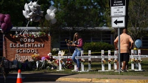Tributes and flowers are laid by white crosses with the names of those killed, at the gates of Robb Elementary School in Uvalde