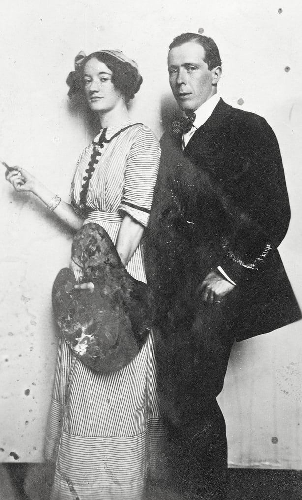 Grace Gifford Plunkett, holding a brush and artist's palette, and William Orpen, three-quarter length portrait, printed on postcard. Grace Gifford studied under the Irish artist William Orpen at the Dublin Metropolitan School of Art between 1904 and 1907.