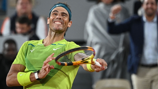 A jubilant Rafael Nadal smacks a ball into the night sky after prevailing on Court Philippe-Chatrier