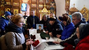 The mother (C) and mourners gather around the coffin of 20-year-old Russian serviceman
Nikita Avrov, during his funeral service in Luga on 11 April
