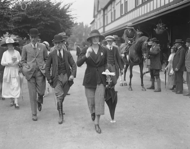 Elegantly dressed people walk past a stand at the Dublin Horse Show in 1922