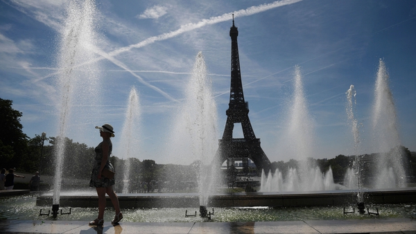 A woman cools off by the Trocadero fountains, amid high temperatures in Paris today