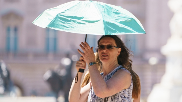 A woman uses an umbrella to shield her face from the sun in London