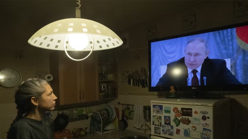 A young woman watches a TV broadcast by Russian president Vladimir Putin. Photo: Anatoly Maltsev/EPA-EFE