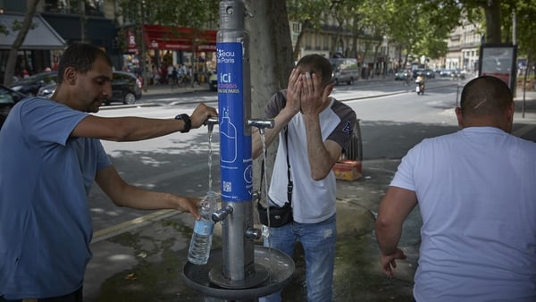 People cool down at a water fountain in Paris