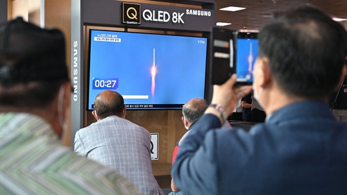 People watch a television screen showing a live footage of Nuri's launch at a railway station in Seoul