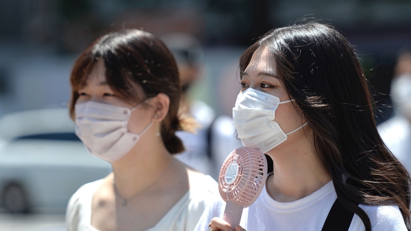 A uses a portable fan to cool down in Tokyo's Shibuya district