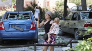 A woman and child walk among destroyed buildings and cars after a Russian missile strike in the Ukrainian town of Serhiivka, near Odesa