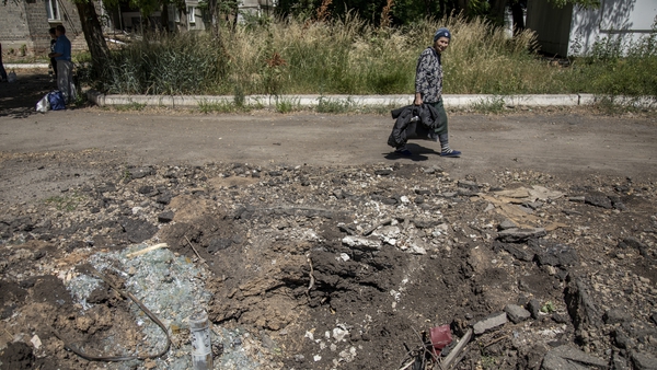 A local civilian walks near a crater left by a rocket explosion in a residential area in Avdiivka