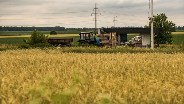 A tractor drives past a checkpoint near a wheat field in Kyiv region, Ukraine