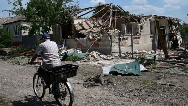 A cyclist rides past a destroyed house, hit by an overnight airstrike, in northern Sloviansk