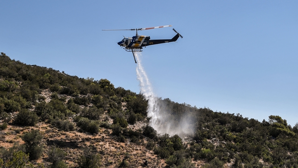 A firefighting helicopter dropping water during a training session in Magoula, Greece