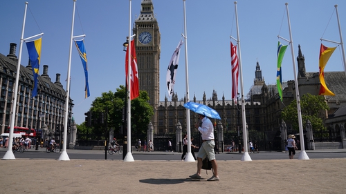 A man uses an umbrella to shield the sun in Westminster