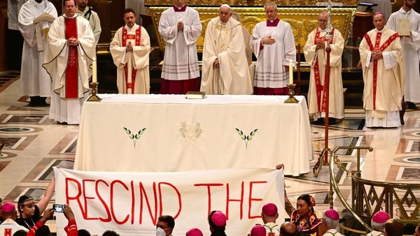 Indigenous people hold a protest banner as Pope Francis celebrates Mass in Quebec, Canada