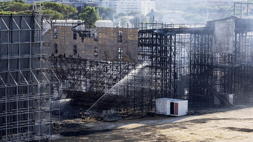 Firefighters hose down a structure to extinguish a fire at the Cinecitta studios southeast of Rome
