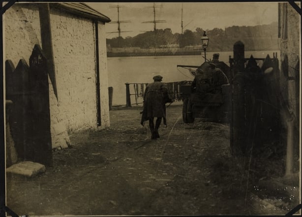 A soldier hunched down to dodge a sniper between two buildings