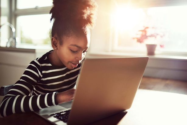 Young black girl working at a laptop at home