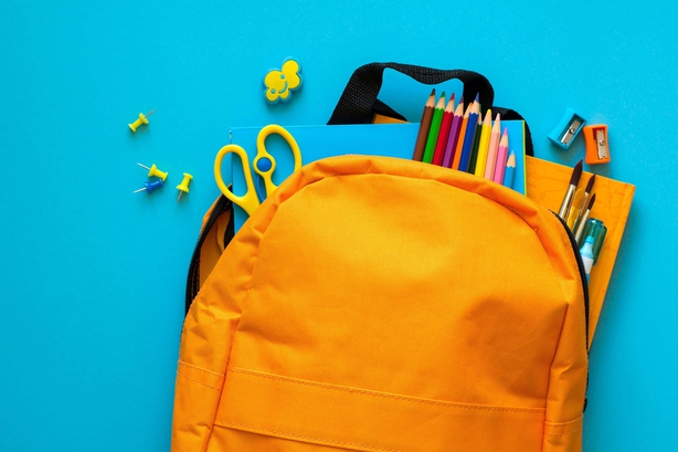 A bright orange school bag with various items of stationery poking out the top
